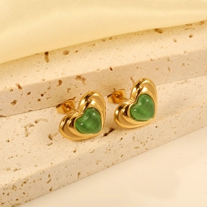Elegant gold heart earrings featuring green crystal stones on a natural stone background