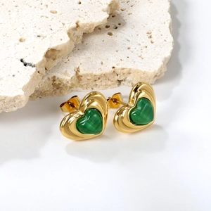 Detail of heart stud earrings in gold with green malachite inlay on stone base