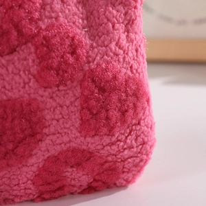 Close-up of soft plush texture on a pink checkerboard makeup bag with fluffy heart pattern