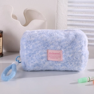 Detail of light blue faux fur makeup bag with soft texture and pink fabric label