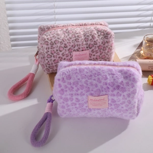 Plush leopard print makeup bags in pink and purple with wristlet handles and zippers