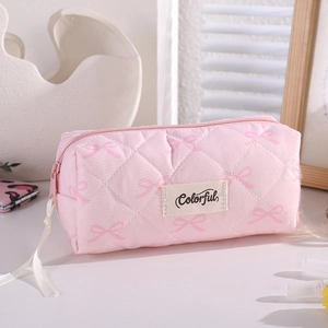 Close-up of pink quilted makeup bag with bow patterns and Colorful woven label