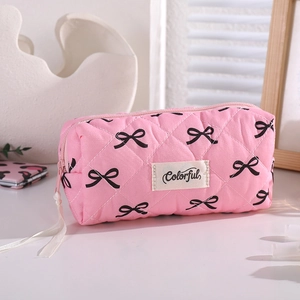 Detail of pink quilted pencil case with bow patterns, ribbon zipper and textile label