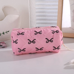 Detailed view of pink quilted fabric pencil case featuring small black bow tie patterns