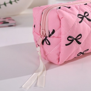 Detailed close-up of pink quilted pencil case featuring bow prints and ribbon zipper pull