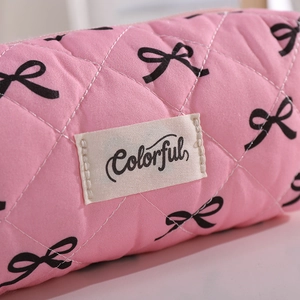 Detail of pink quilted pencil case with black bow patterns and colorful woven label