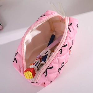 Pink quilted pouch with black bow prints showing interior capacity for pens and brushes