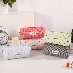 Detailed view of quilted fabric pencil cases with cherry pattern in five vibrant colors
