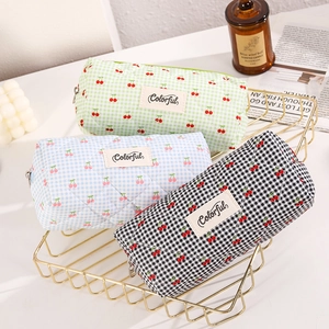 Quilted canvas pencil cases with cherry patterns and colorful label in a gold wire basket
