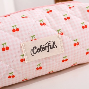 Detail of pink plaid quilted pencil case with red cherry print and Colorful label