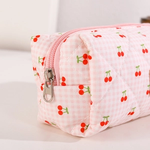 Detail of pink quilted fabric pen case featuring cherry prints and smooth silver zipper