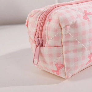 Dettaglio della borsa cosmetica a scacchi rosa che mostra la trama trapuntata e il fiocco