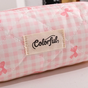 Dettaglio della trousse trapuntata a quadretti rosa con motivi a fiocco ed etichetta