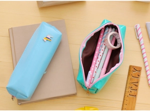 Flat lay of light blue and mint green PU leather pencil cases with pony charms on a wooden desk