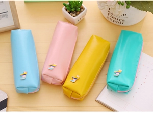 Close-up of pastel PU leather pencil cases with cute animal metal ornaments on a desk
