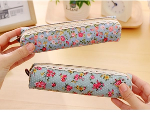 Close-up of floral canvas pencil cases with lace trim and metal zipper on wooden desk