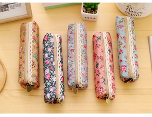 Detail showing vintage floral canvas pencil cases with white lace trim and metal zippers