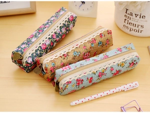 Detail of floral and polka dot canvas pencil cases with lace trim on a wooden desk