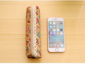 Detail of floral canvas pencil case with vintage lace trim and metal zipper closure