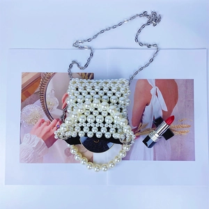 Détail du mini sac à main en perles tissées avec chaîne argentée sur un magazine