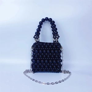 Détail de la texture d'un sac à main en perles noires avec chaîne en métal argenté