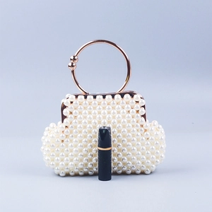 Detailed view of white pearl beaded evening handbag with rose gold metal ring handle