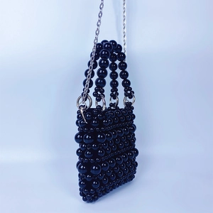 Détail du sac à bandoulière tissé à la main en perles noires avec chaîne argentée