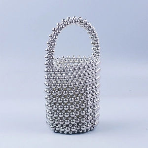 Gros plan sur un sac seau à perles argentées avec un tissage évidé réfléchissant
