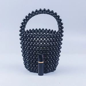 Détail d'un sac seau en perles noires avec rouge à lèvres pour l'échelle de taille