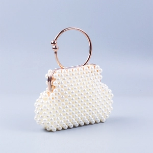 Close-up of handmade pearl clutch bag with rose gold circular metal handle and beads