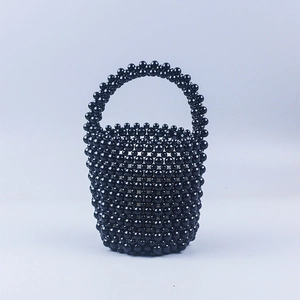 Détail d'un sac seau fait main en perles noires avec texture tissée brillante et anse