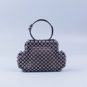 Detail of hand-woven dark grey beaded shell bag with large circular metal top handle