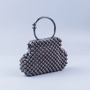 Detailed view of dark grey beaded evening bag with a metallic round handle and clasp