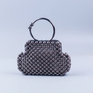 Detail of dark grey metallic beaded handbag with structured shell texture and ring handle