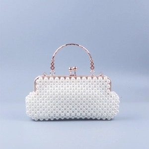Detailed view of white pearl evening bag featuring rose gold round metal handle and floral carving