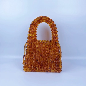 Detail of amber acrylic beaded handbag showing handmade weaving and vintage hollow pattern