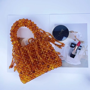 Detail of amber beaded handbag with tassels and acrylic pearls on a magazine