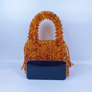 Detail of amber acrylic beaded bag with fringe and phone for size reference