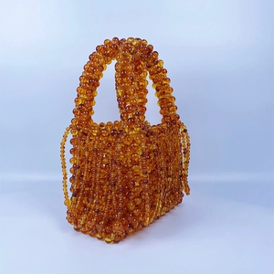 Detailed view of amber beaded handbag featuring woven acrylic beads and fringe tassels