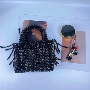Detail of handmade black beaded handbag with fringe tassels and fashion magazine accessories
