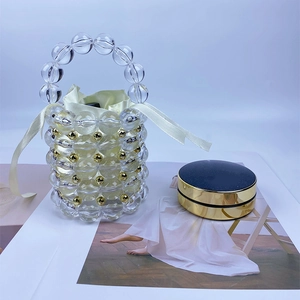 Detail of beaded bucket bag showing transparent acrylic beads and gold metal spheres