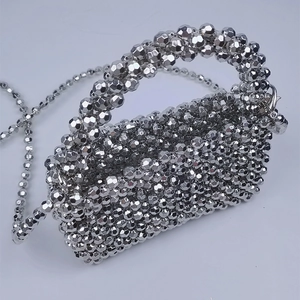 Detailed close-up of a silver beaded mini bag with metallic texture and crossbody chain