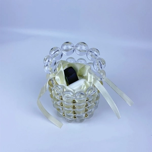 Detail of beaded handbag featuring transparent acrylic beads and a yellow satin drawstring pouch