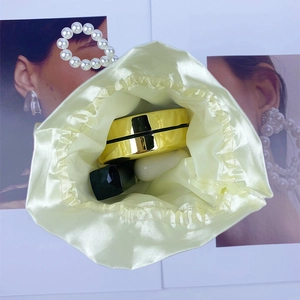 Detail of champagne satin drawstring pouch showing cosmetics for capacity reference