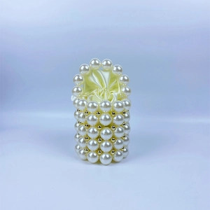 Close-up of pearl beaded handbag featuring gold accents and a satin drawstring liner