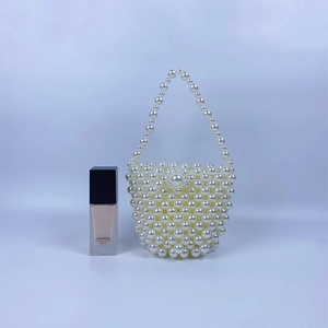 Detail of handcrafted cream pearl bucket bag showing floral clasp and woven texture