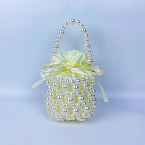 Detail of handmade pearl bucket bag with hollow woven design and yellow satin inner lining