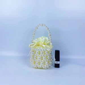 Detail of handmade pearl bucket bag with yellow satin drawstring lining and handle