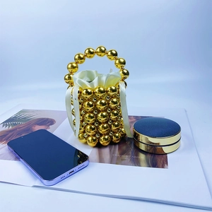 Close-up of golden beaded handbag with drawstring satin lining and small makeup items