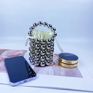 Close-up of DIY beaded bucket bag with metallic silver beads and yellow satin drawstring